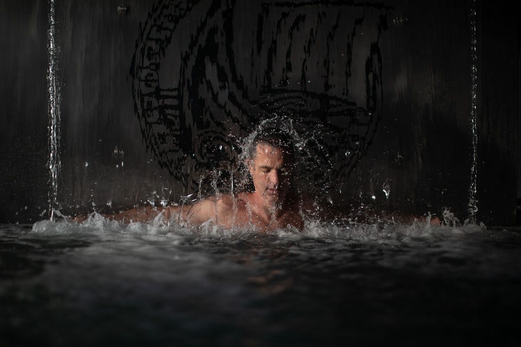 Thermal therapy guide Scott Simons enjoys hot cascading water from the thermal waterfall located at the spectacular indoor hot pool at Scandinave Old Montreal as part of his spa journey.