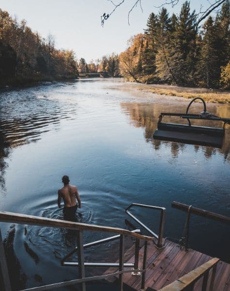 A man wading into a river to cool off at Scandinave Spa