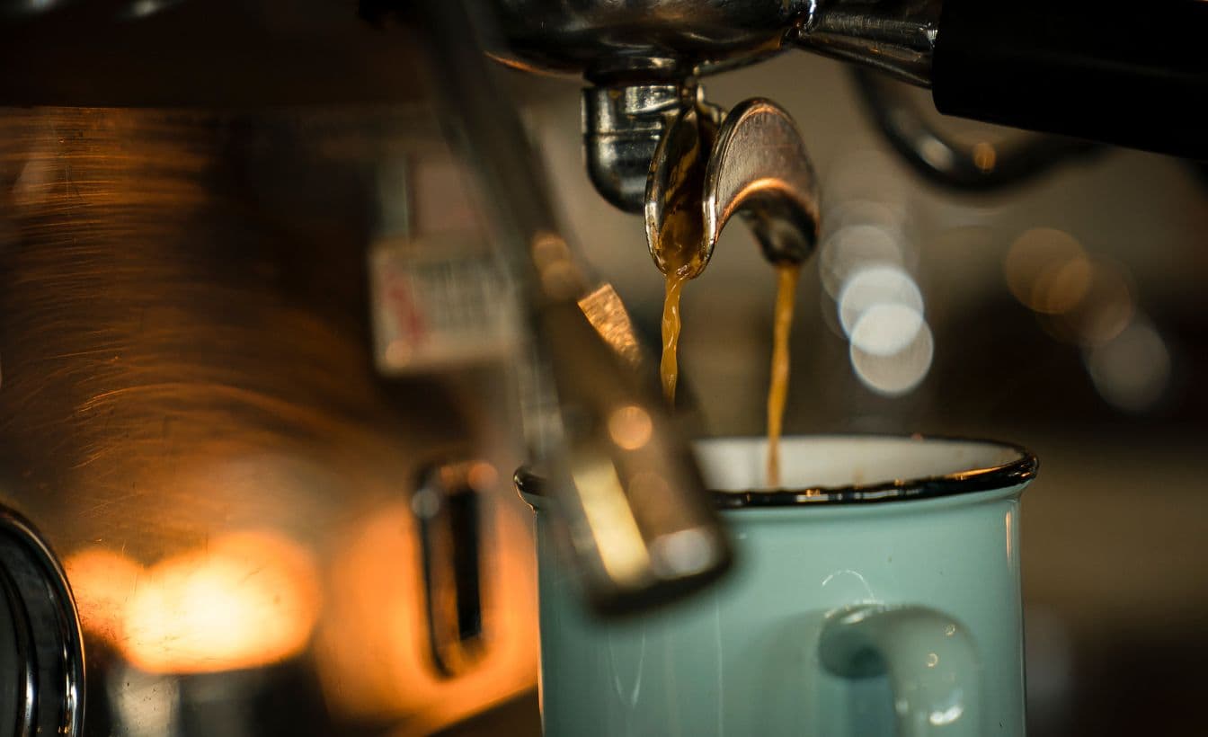 espresso pours into a mug with an early morning glow at Scandinave Spa Whistler