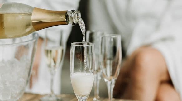 A chilled bottle of sparkling dealcoholized wine is poured into champagne flutes in the lounge area at Scandinave Spa Whistler