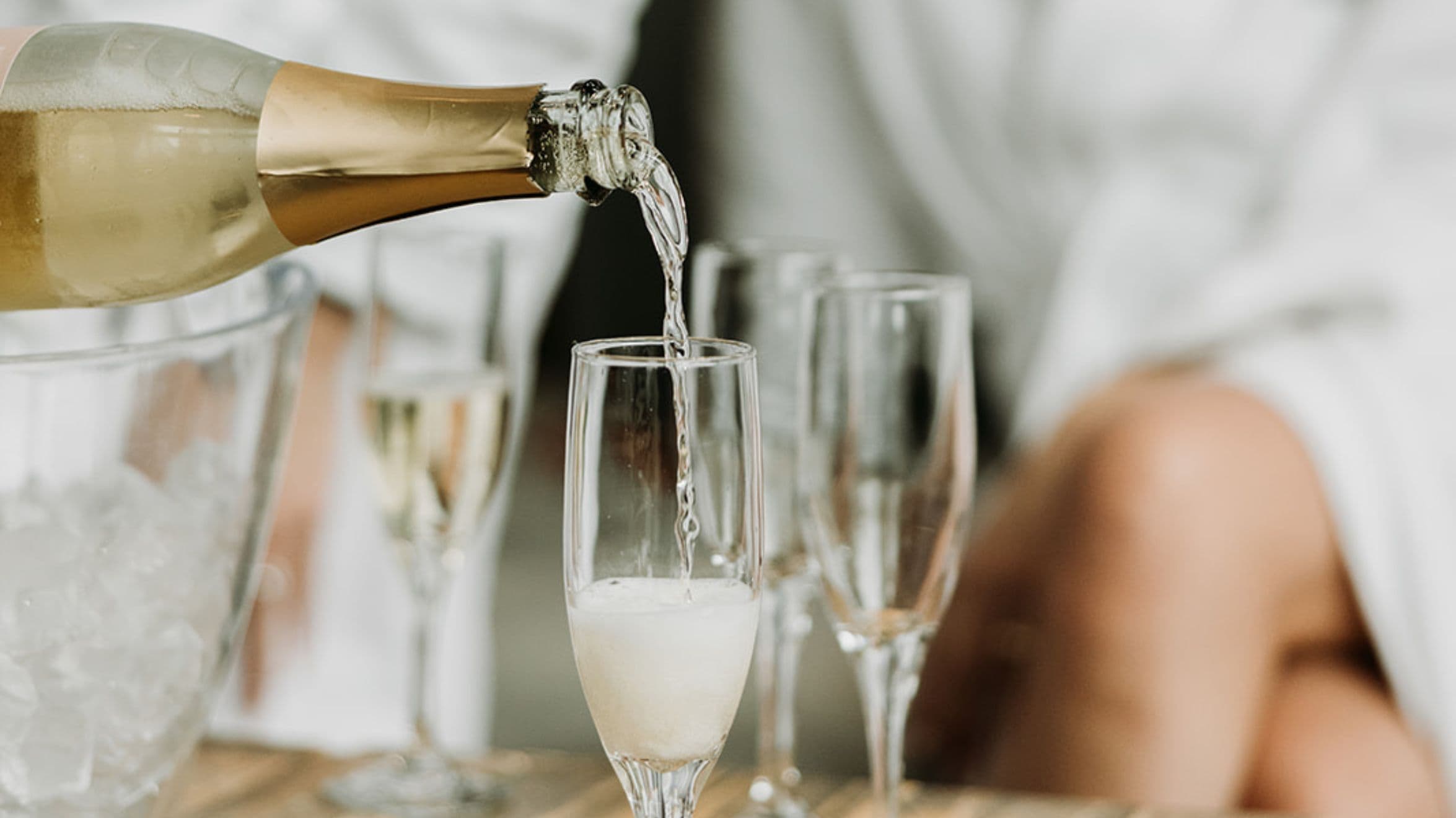 A chilled bottle of sparkling dealcoholized wine is poured into champagne flutes in the lounge area at Scandinave Spa Whistler.