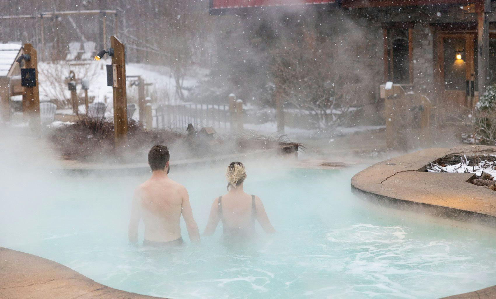 couple relaxing in outdoor hot Bath in winter at Scandinave Spa Blue Mountain.