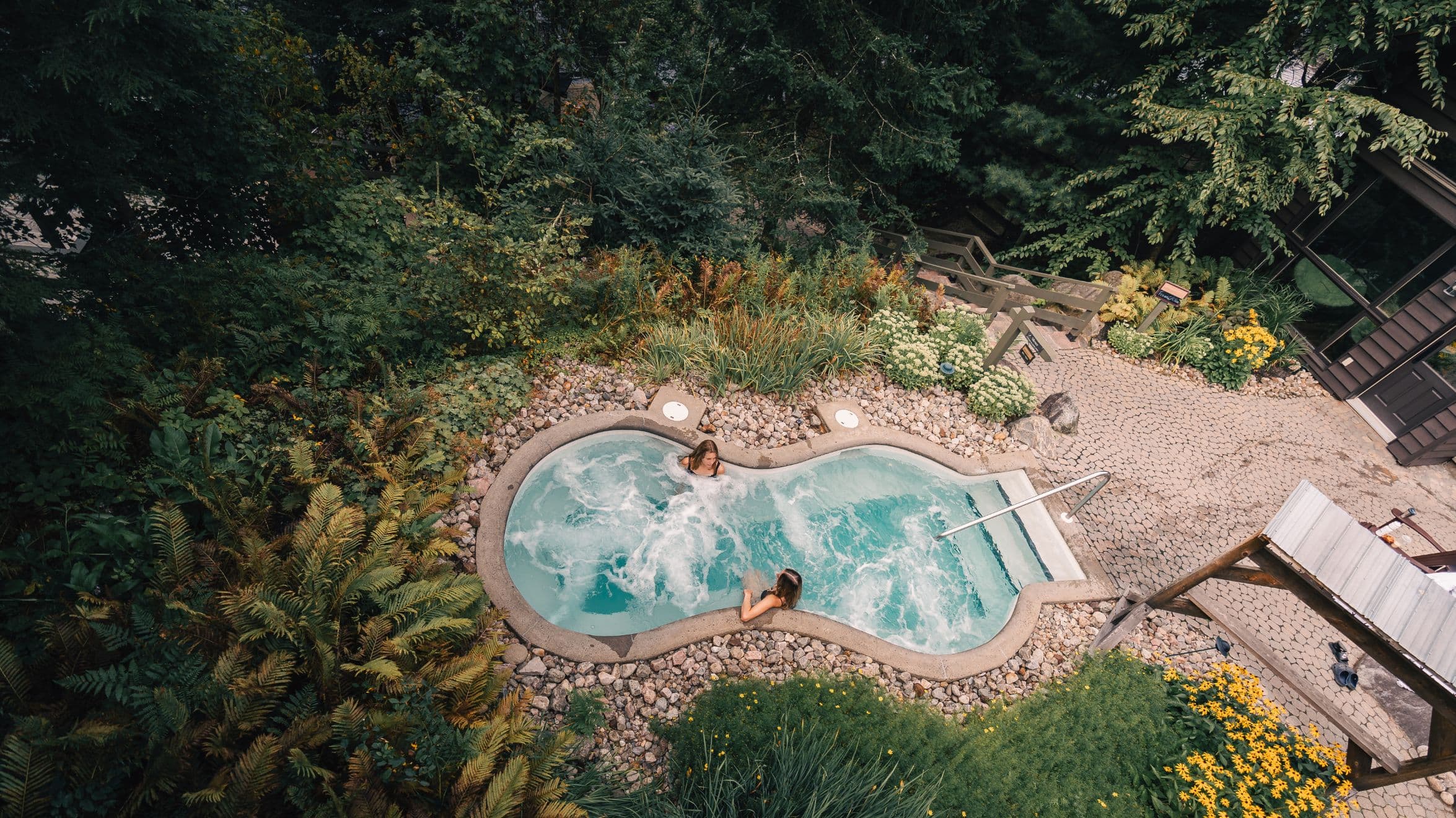 Deux femmes profitant d’un spa chaud en pleine nature au Scandinave Spa Mont-Tremblant, un moment de détente tout en silence.