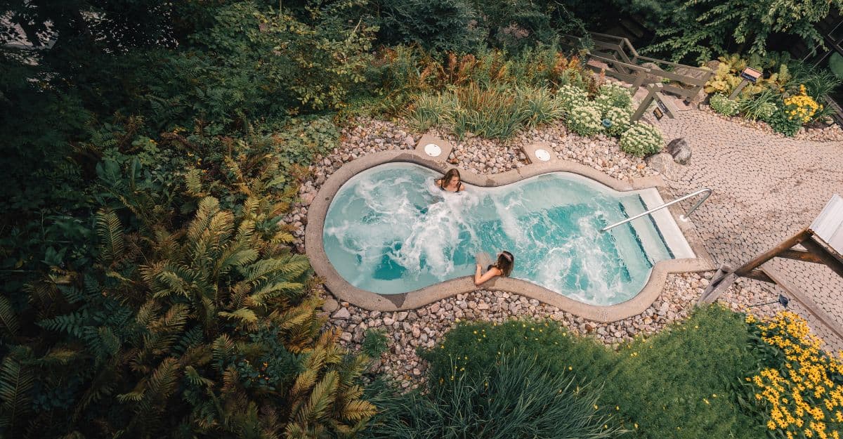Two women enjoying thermotherapy in a hot outdoor pool surrounded by nature at Scandinave Spa Mont-Tremblant.