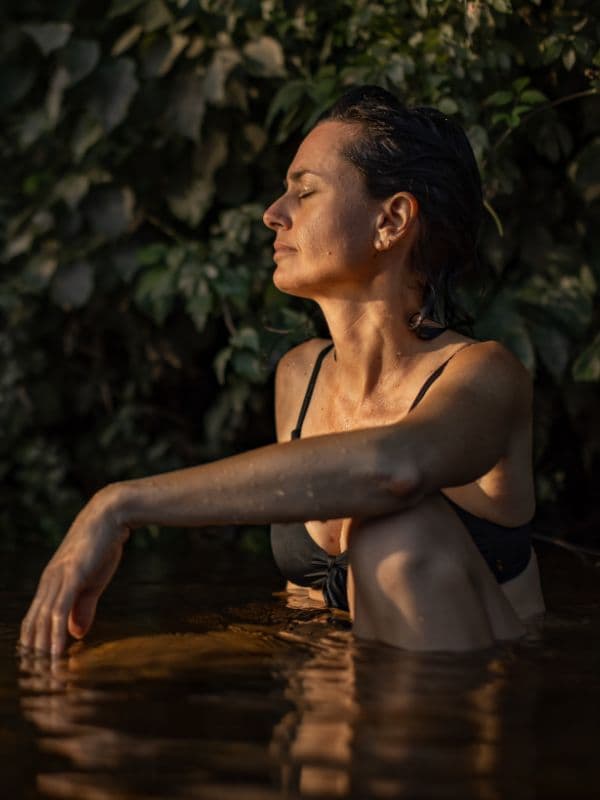 Close-up of a woman relaxing in the river under the sun, enjoying a moment of serenity at Scandinave Spa Mont-Tremblant.