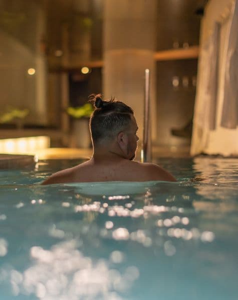 A man seen from behind in the hot pool, in the evening, at Scandinave Spa Vieux-Montréal.