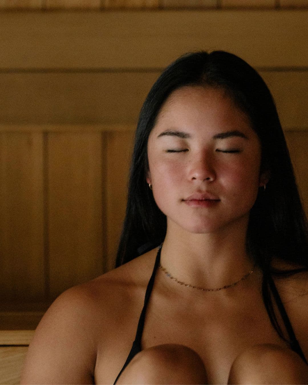 A close-up of a woman's face in the dry sauna at Scandinave Spa Whistler, immersed in a moment of deep relaxation.