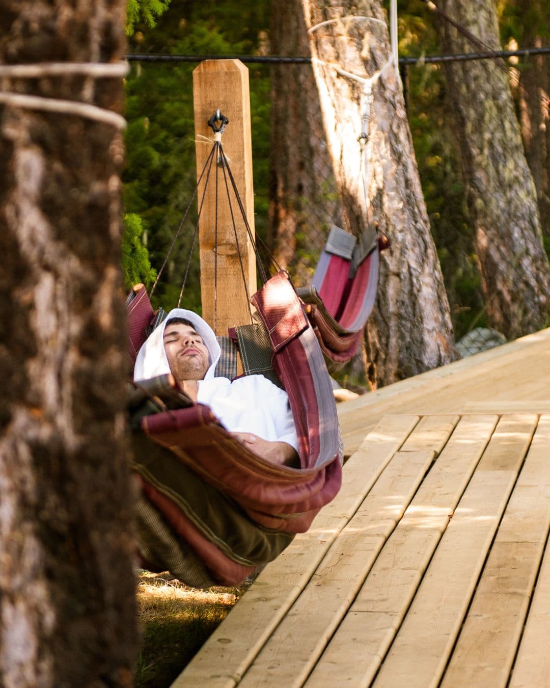 A man relaxing in a hammock, surrounded by nature at Scandinave Spa Whistler, enjoying the tranquility.