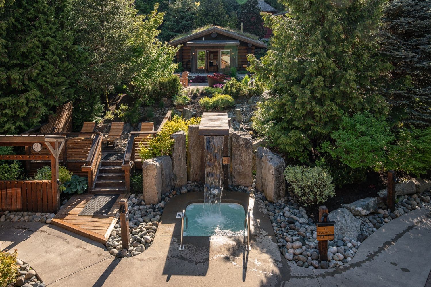 Wood-burning sauna and Nordic waterfall surrounded by lush summer greenery at Scandinave Spa Whistler.